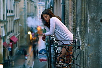 Woman Smoking on Balcony in European City Street