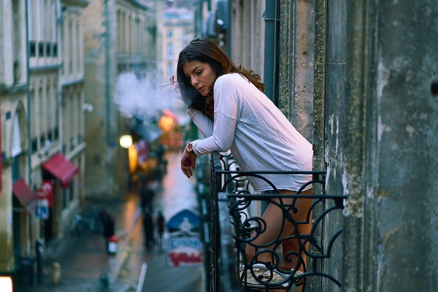 Woman Smoking on Balcony in European City Street