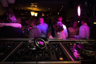 DJ mixing console and headphones at a crowded nightclub party