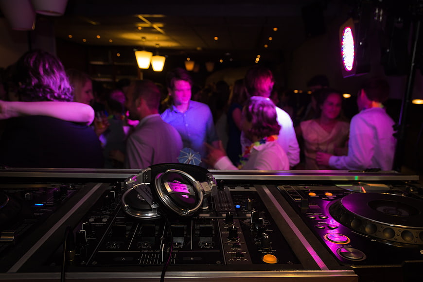 DJ mixing console and headphones at a crowded nightclub party