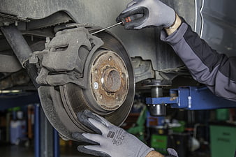 Mechanic Repairing Car Brake Disc in Auto Workshop