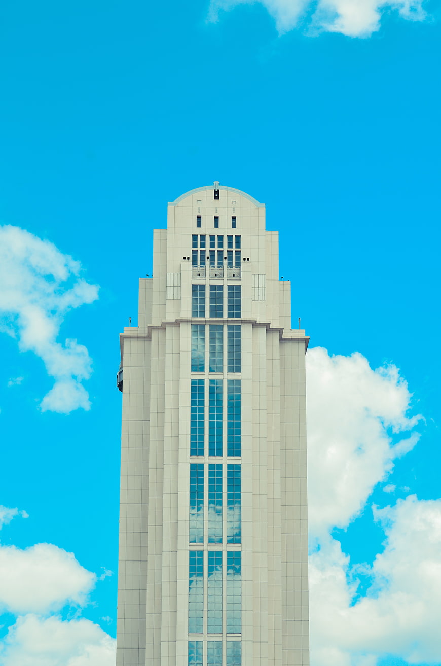 Tall white skyscraper against blue sky with clouds