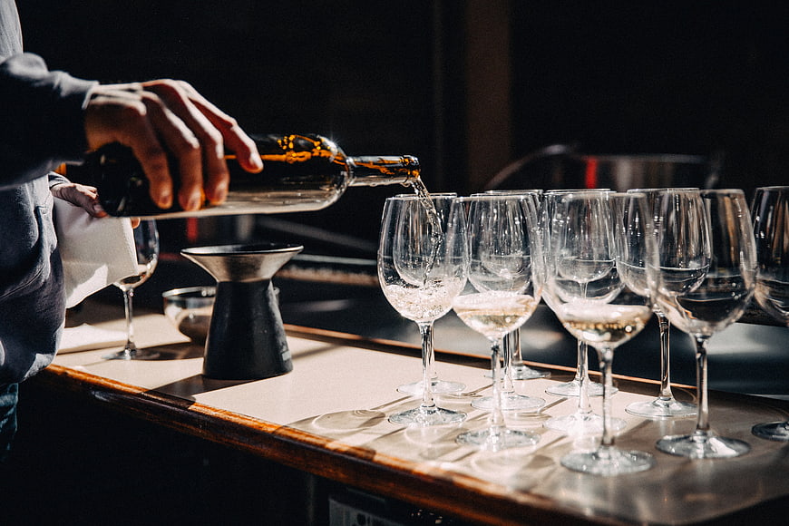 Bartender Pouring White Wine into Glasses at Bar