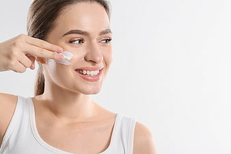 Happy Woman Applying Skincare Cream to Face