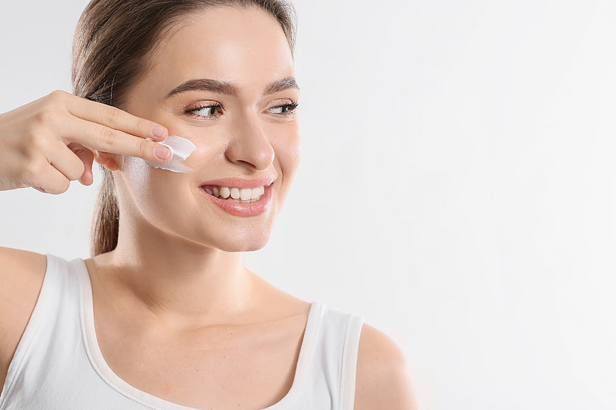 Happy Woman Applying Skincare Cream to Face