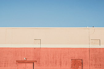 Minimalist red and beige building wall under blue sky