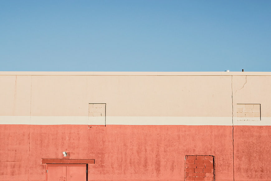 Minimalist red and beige building wall under blue sky