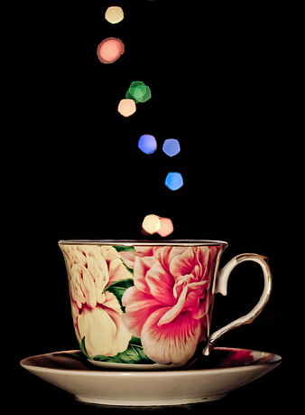 Floral teacup with colorful bokeh lights on black background