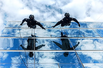 Two soldiers rappelling down a glass skyscraper facade