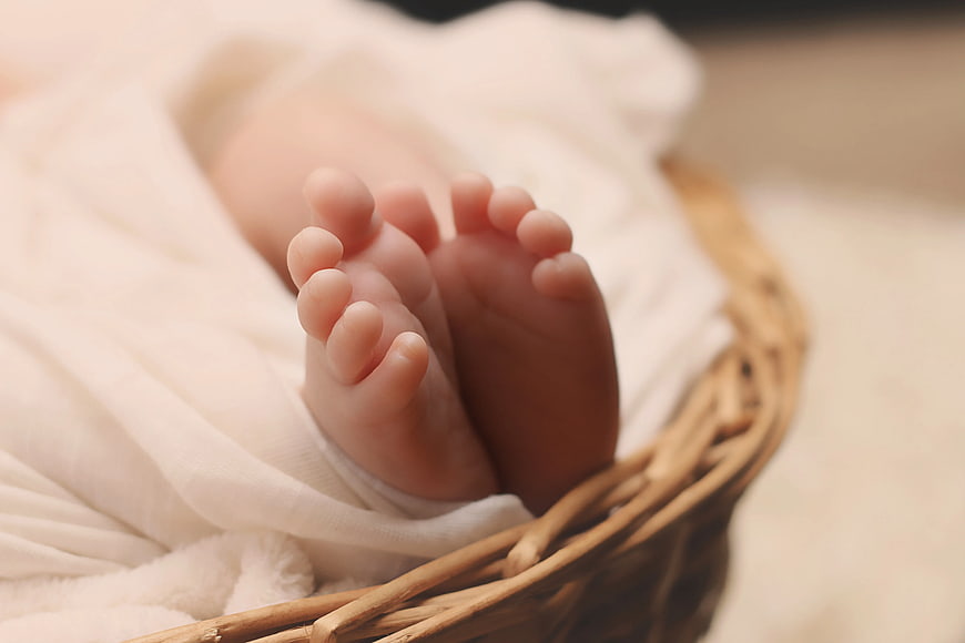Close-up of newborn baby feet in wicker basket