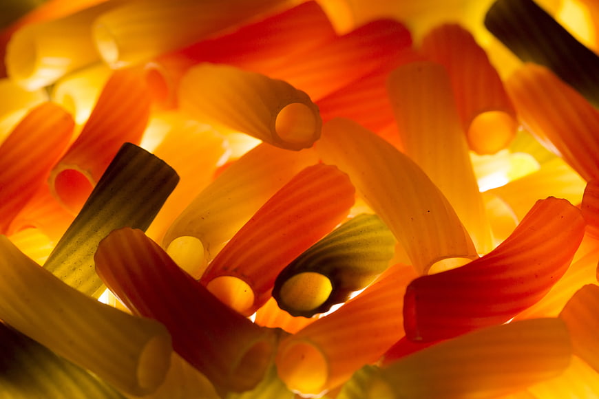 Close-up of colorful penne pasta with warm backlighting