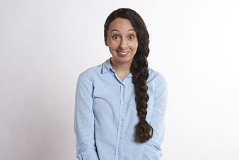 Portrait of a surprised young woman with a long braid in a blue shirt