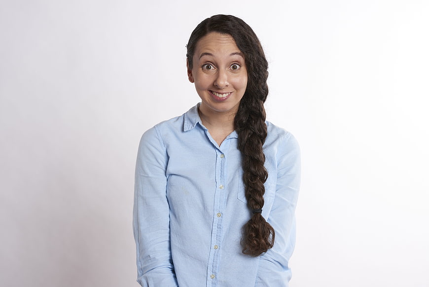 Portrait of a surprised young woman with a long braid in a blue shirt