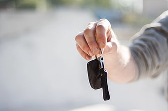Hand Holding Car Keys Against Blurred Background