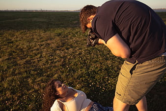 Photographer taking photo of woman lying in grassy field