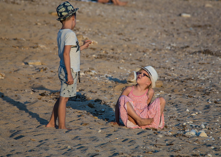Two children playing on a sandy beach in summer