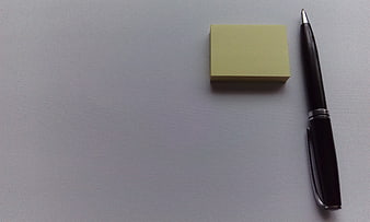 Minimalist Office Desk Setup With Black Pen And Yellow Sticky Note