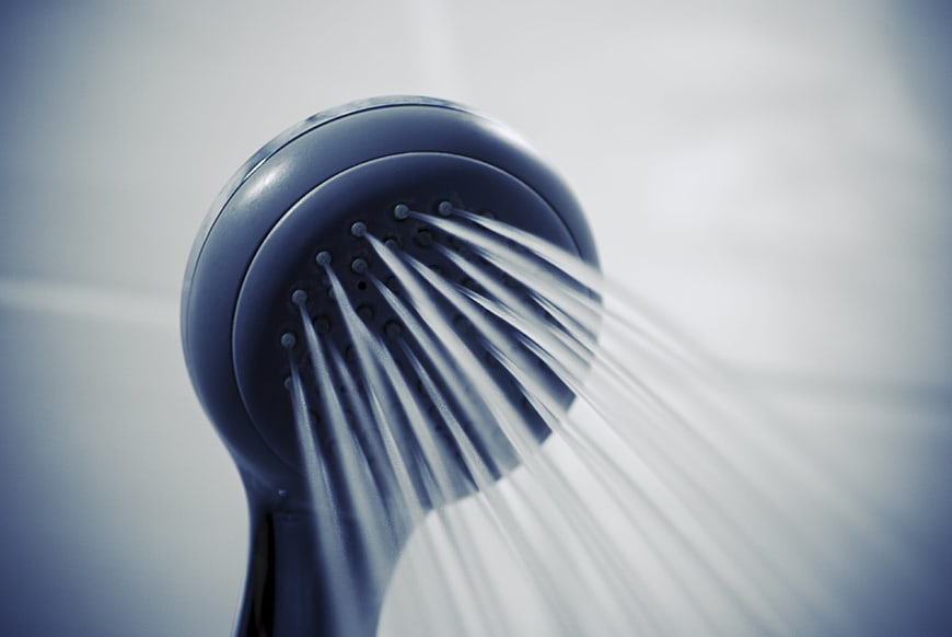 Close-up of blue shower head spraying water streams