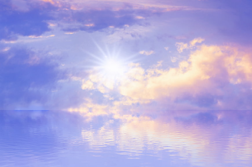 Serene pastel sunset sky with sun reflection on calm water