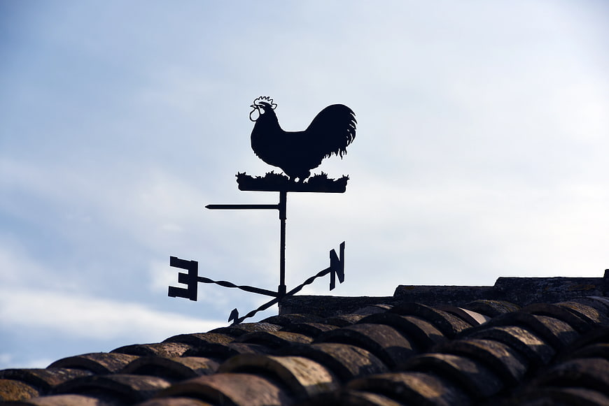 Silhouette of Rooster Weather Vane on Tiled Roof
