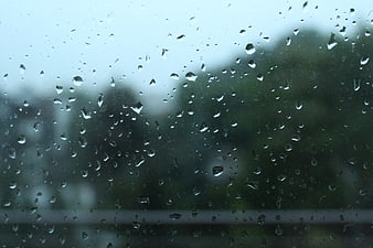 Raindrops on glass window with blurred green background