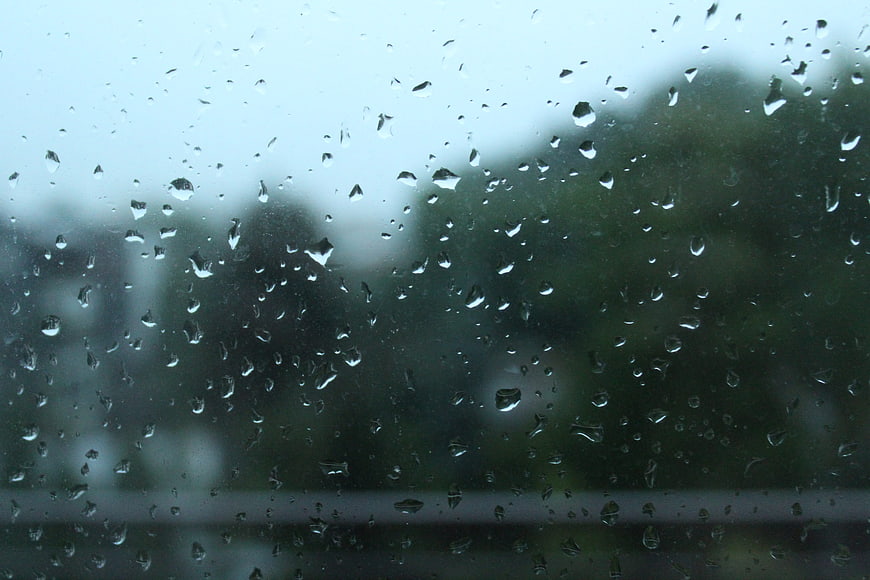 Raindrops on glass window with blurred green background