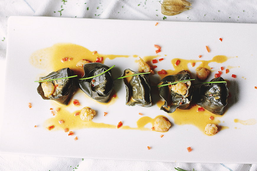 Gourmet stuffed grape leaves with shrimp and sauce on white plate