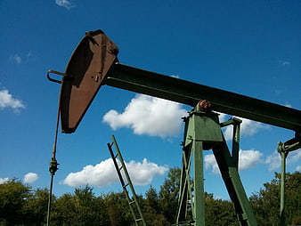 Green Oil Pump Jack Against Blue Sky