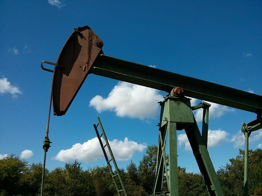 Green Oil Pump Jack Against Blue Sky