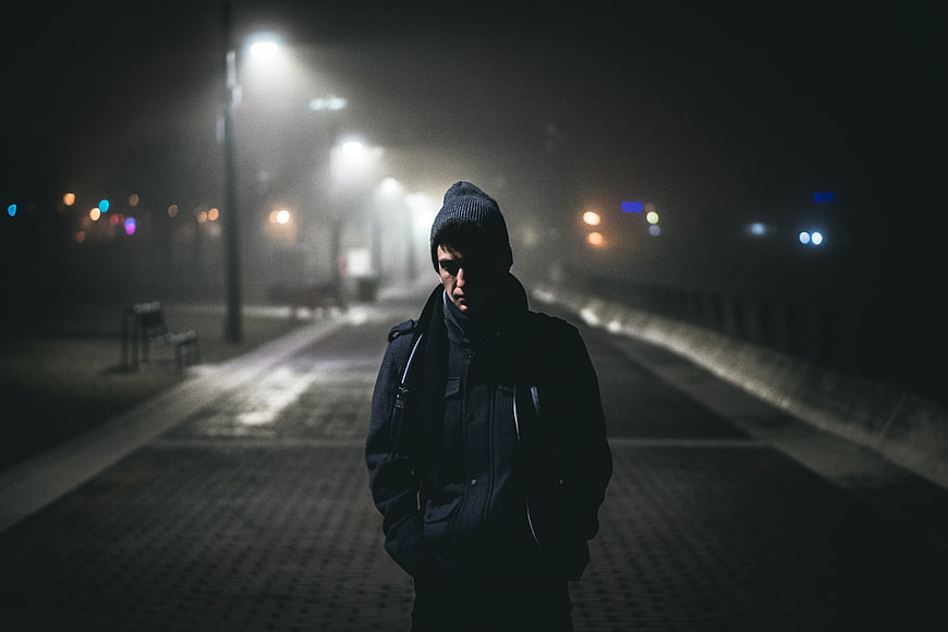 Lonely man walking alone on foggy street at night
