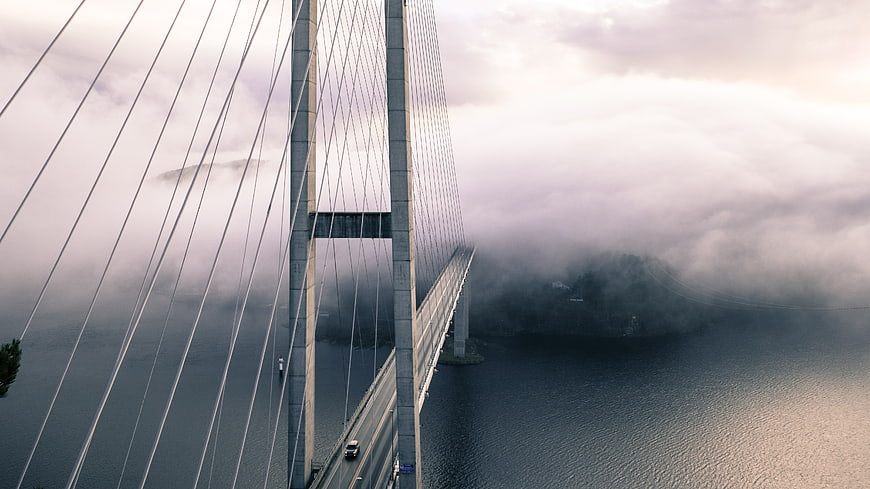 Cable-stayed bridge disappearing into thick fog over water