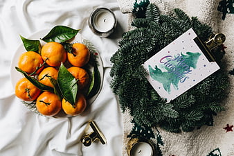 Christmas flat lay with tangerines, wreath, and holiday card