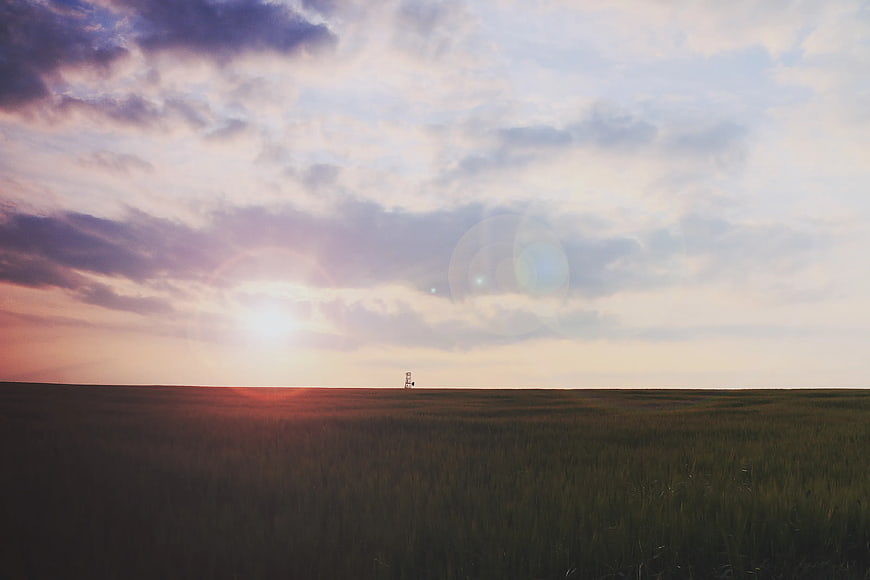 Sunrise Over Vast Grassland With Distant Structure