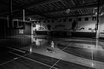 Young boy standing alone on empty basketball court