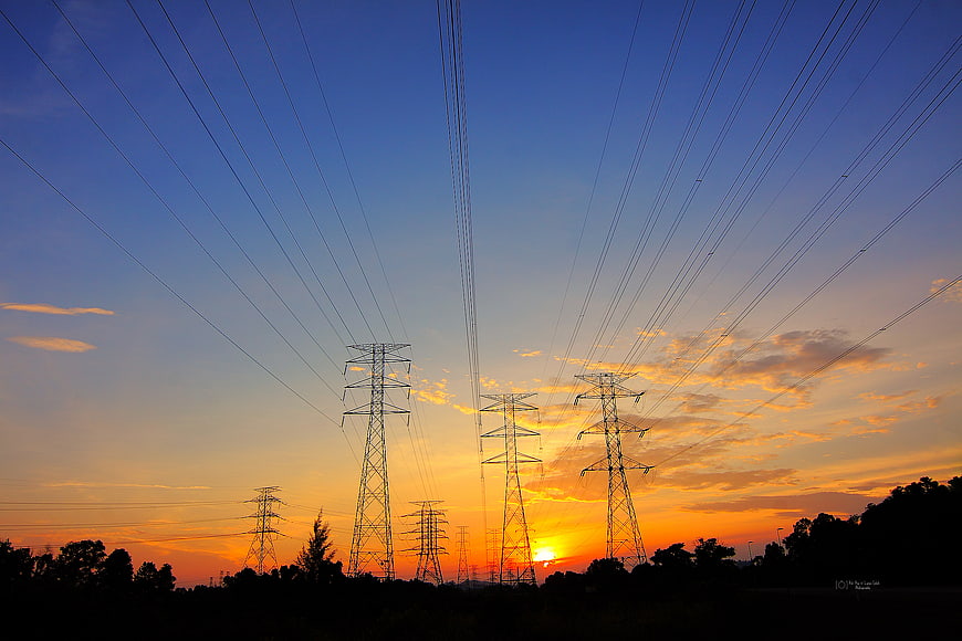 Silhouetted Power Lines Against Vibrant Sunset Sky