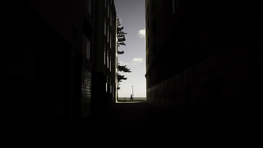 Dark Alleyway Silhouette Leading to Bright Sky