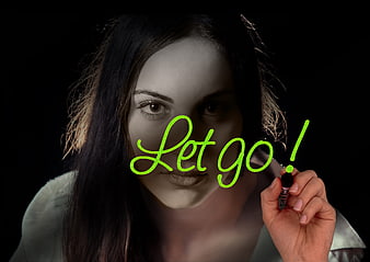 Woman writing let go on glass with neon marker