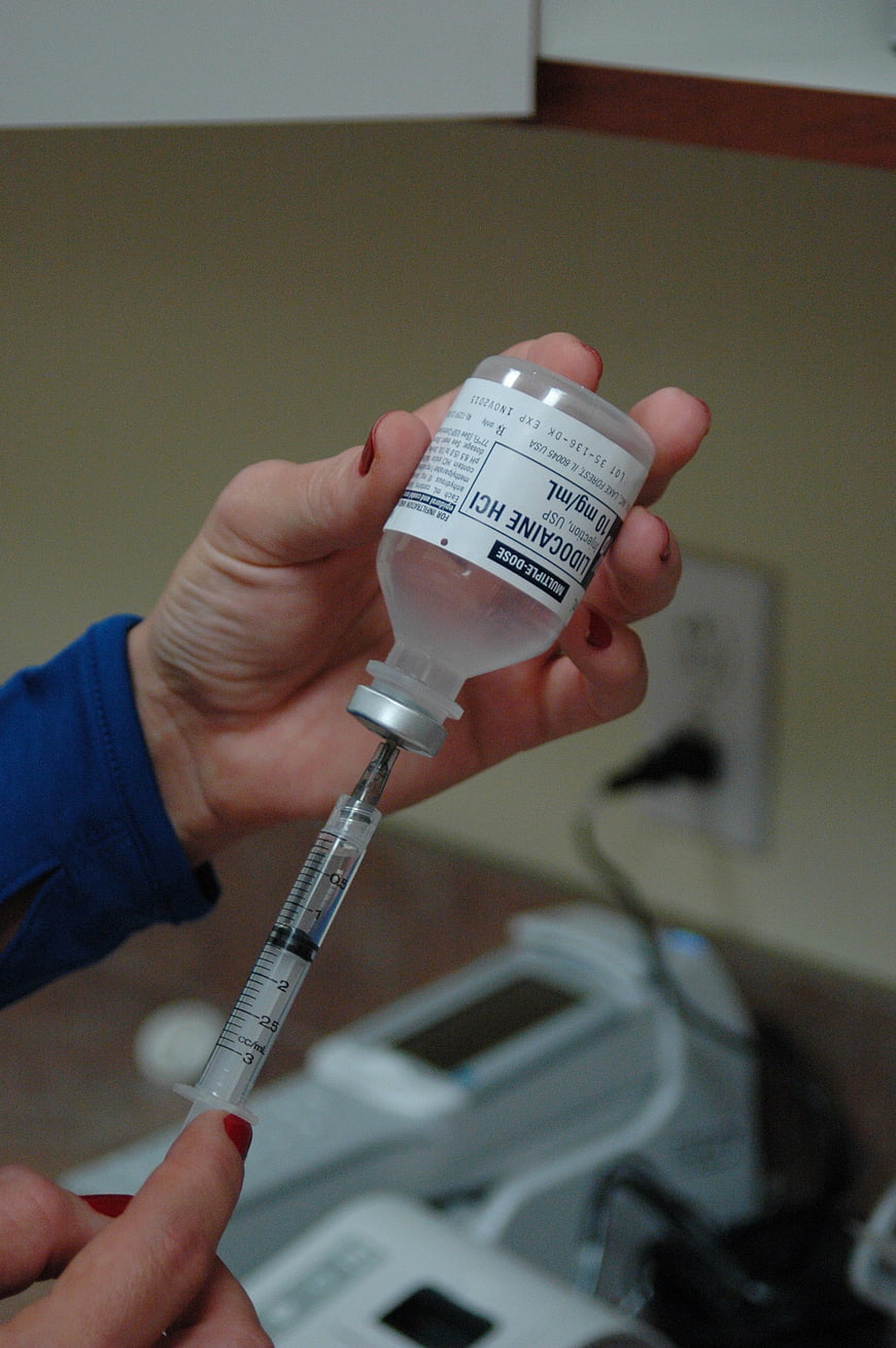 Nurse drawing lidocaine into syringe for injection