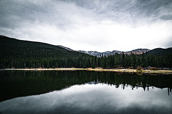 Serene Mountain Lake with Forest Reflection and Cloudy Sky
