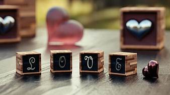 Wooden cubes spelling LOVE with heart ornaments on a rustic table