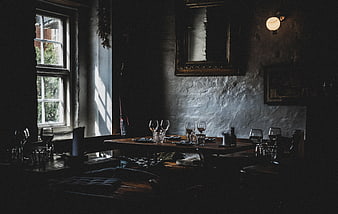 Moody rustic restaurant interior with wine glasses and sunlight