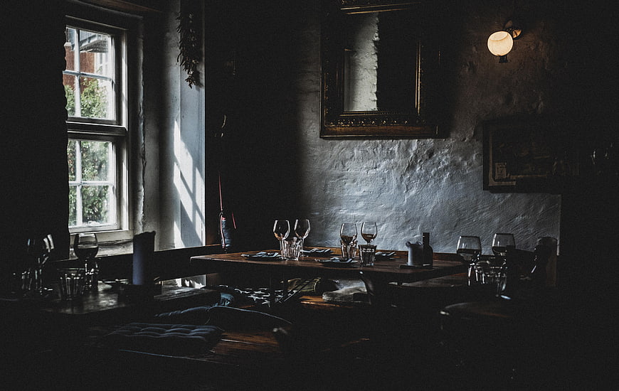 Moody rustic restaurant interior with wine glasses and sunlight