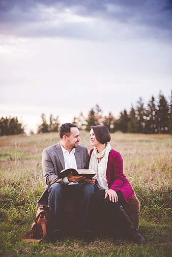 Happy couple reading a book together in a grassy field