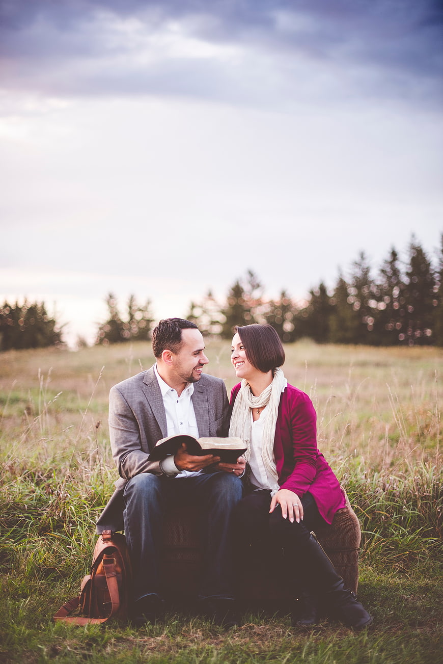 Happy couple reading a book together in a grassy field