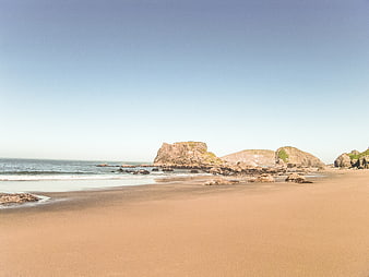 Sandy Beach with Rocky Outcrops and Blue Sky