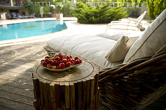 Fresh cherries on wooden table by luxury poolside lounge