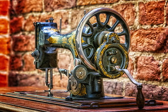 Antique Hand-Cranked Sewing Machine Against Rustic Brick Wall
