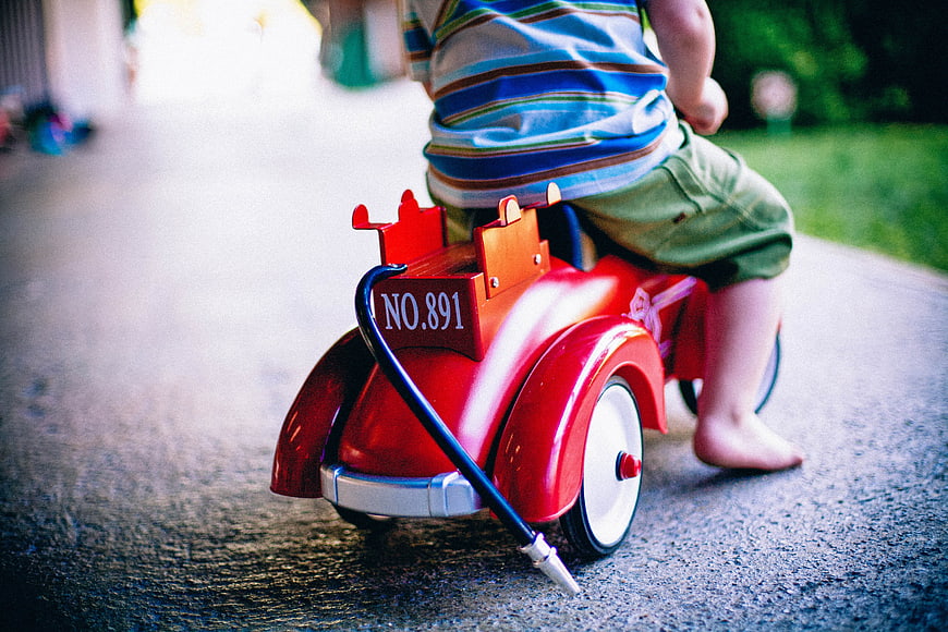 Child Riding Red Vintage Toy Tricycle Outdoors