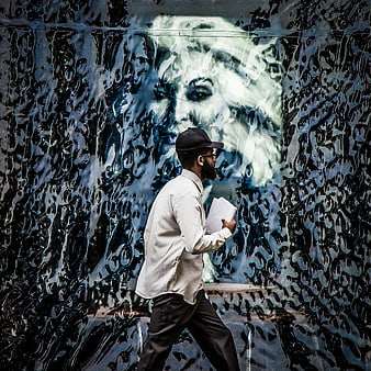 Man walking past textured wall with abstract mural art