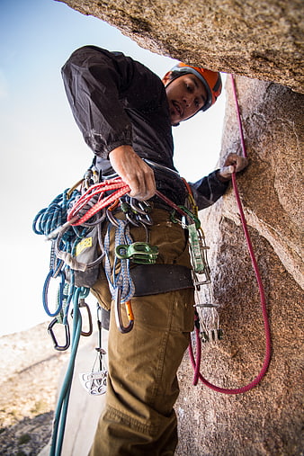 Rock climber adjusting gear on steep granite face